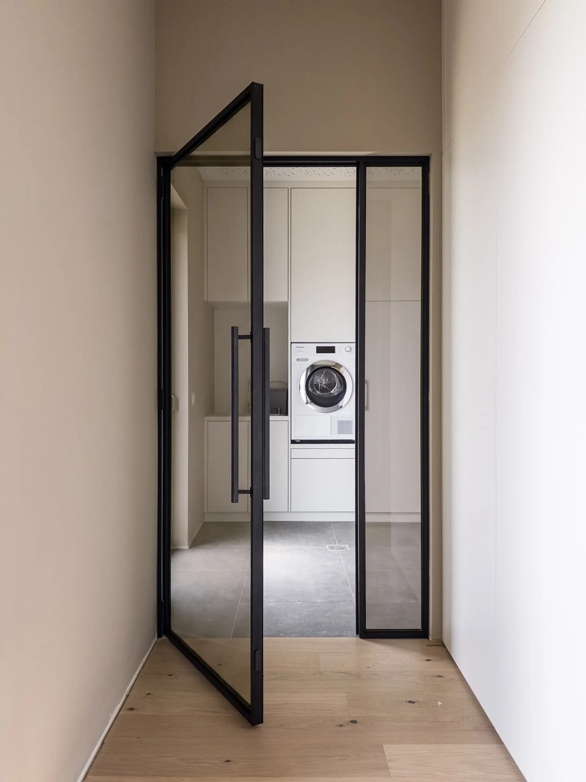 Dieselbe schwarze Drehtür mit Bronzeglas — transparent mit warmer, bronzefarbener Tönung.
