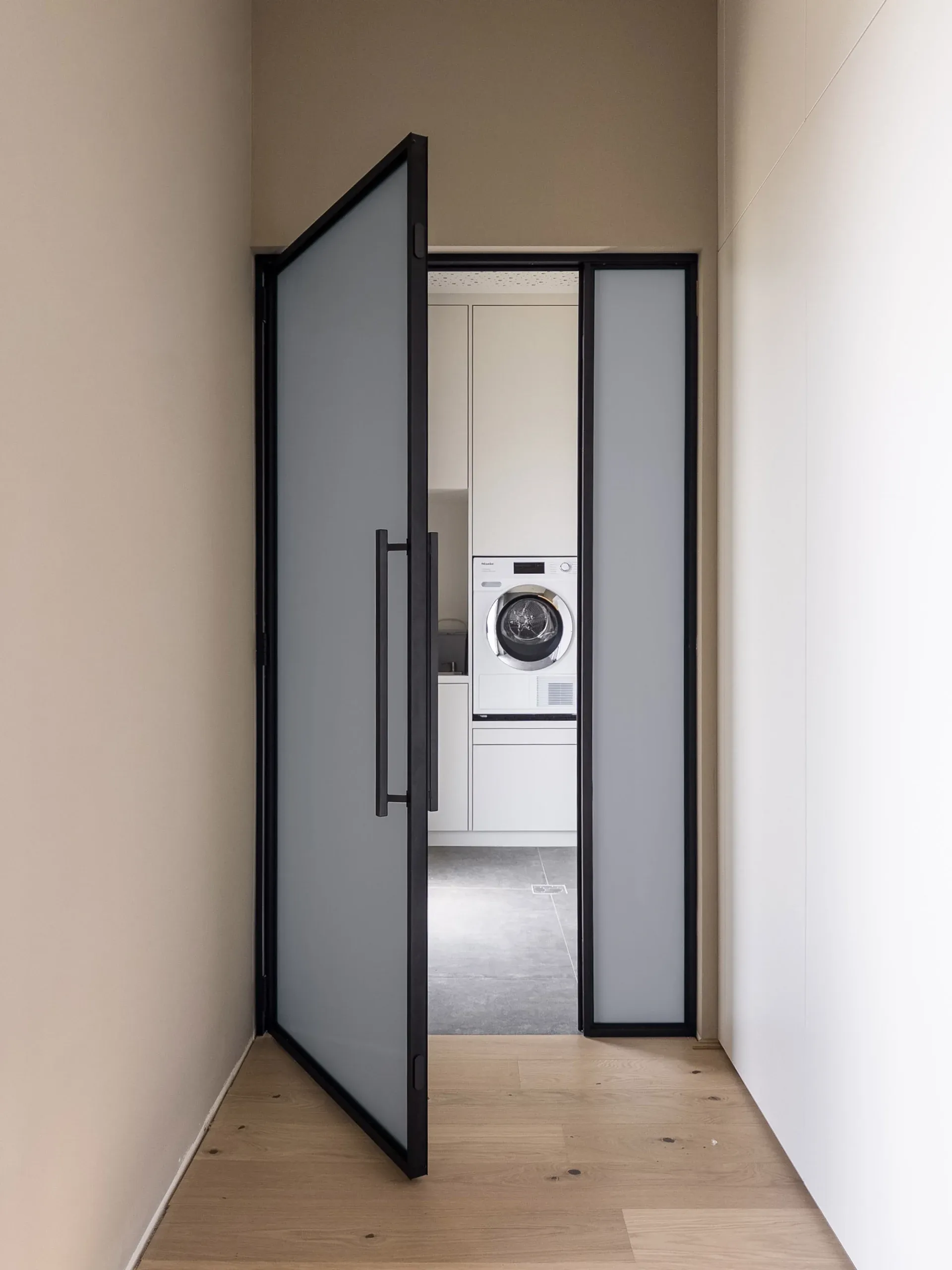 Dieselbe schwarze Drehtür mit grauem Mattglas — blickhemmend in dezenter, kühler Tönung.