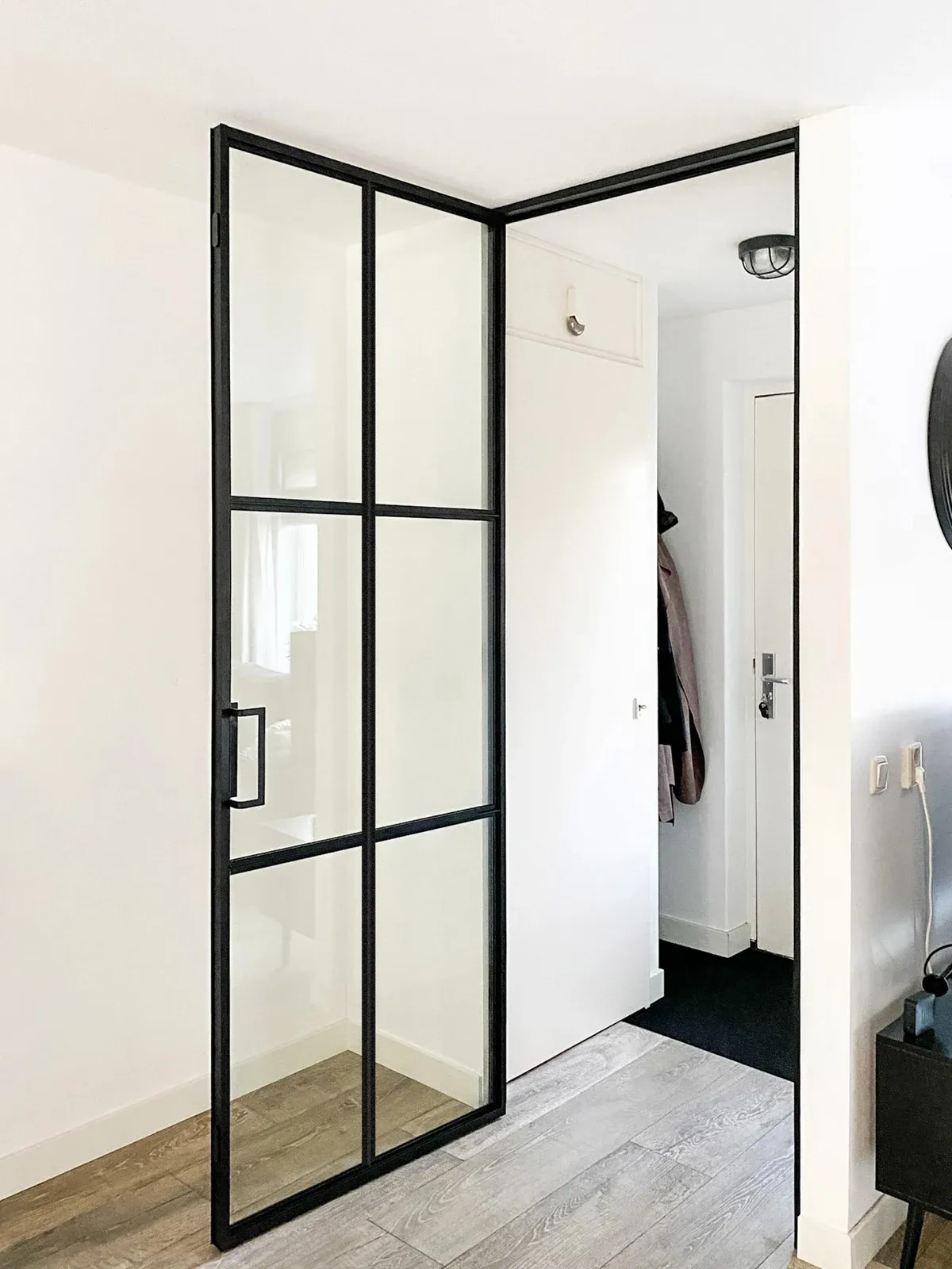 Geöffnete schwarze Drehtür mit symmetrisch gegliederten Glasfeldern.