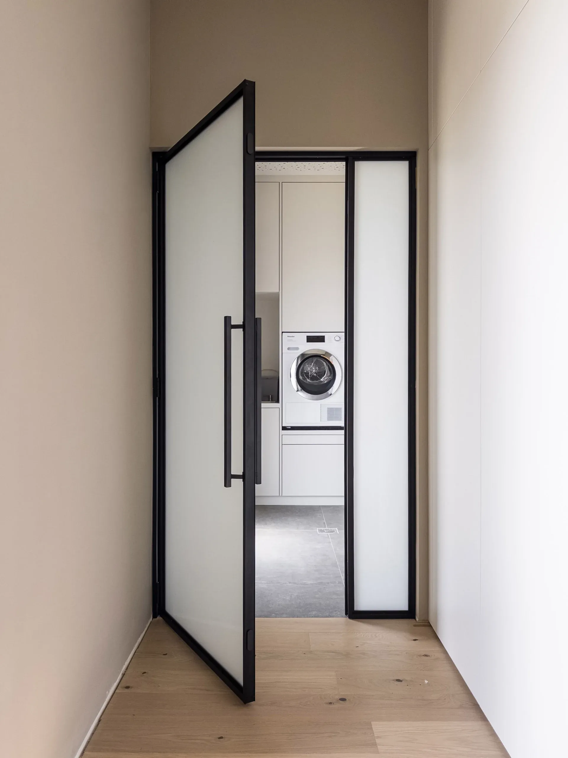 Dieselbe schwarze Drehtür mit Mattglas — blickhemmend mit weicher, heller Lichtwirkung.