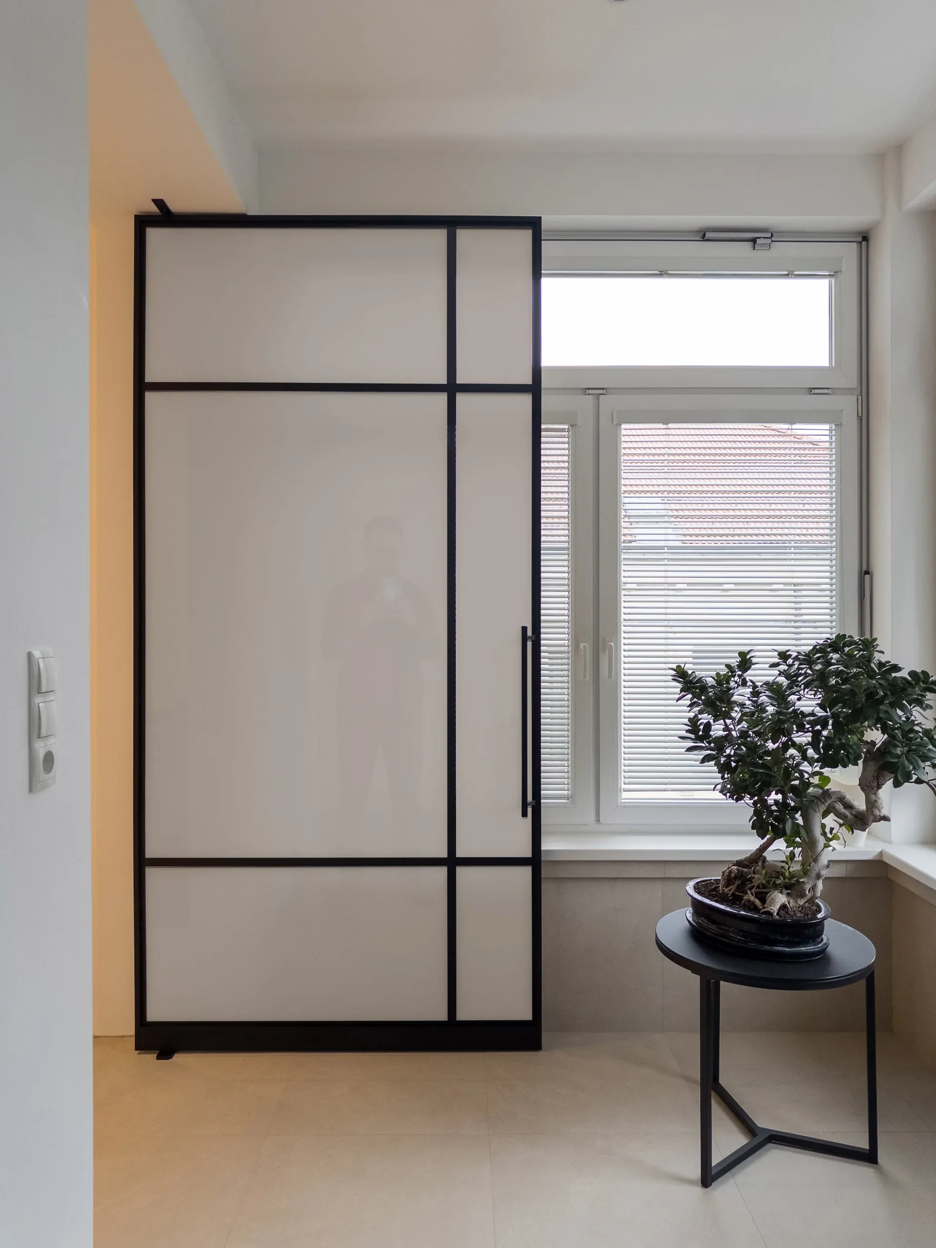 Dieselbe schwarze Pivottür mit bronzefarbenem Mattglas — blickhemmend in warmer Tönung.