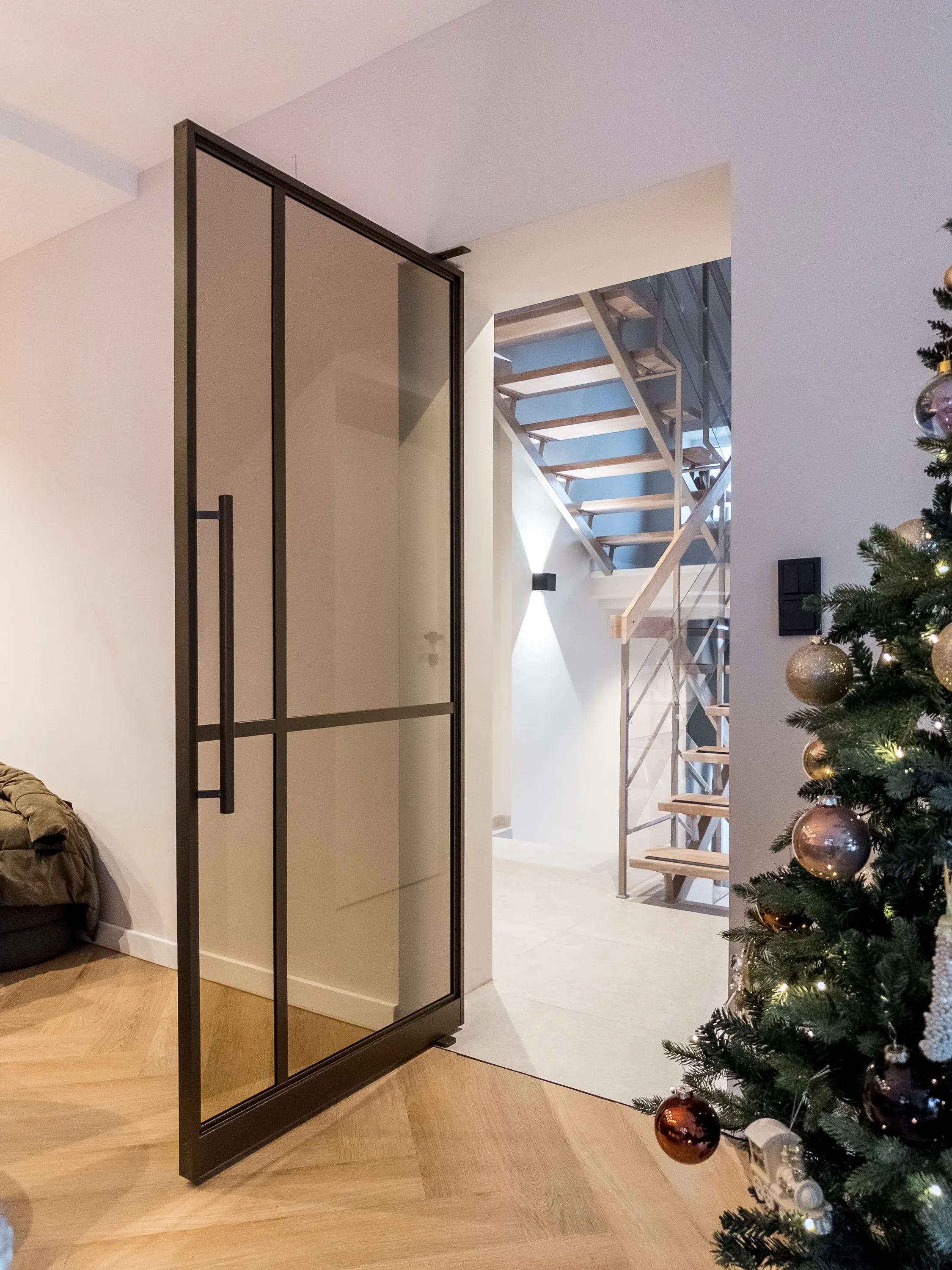Geöffnete Pivottür in Bronze zwischen Wohnzimmer und Stiegenhaus