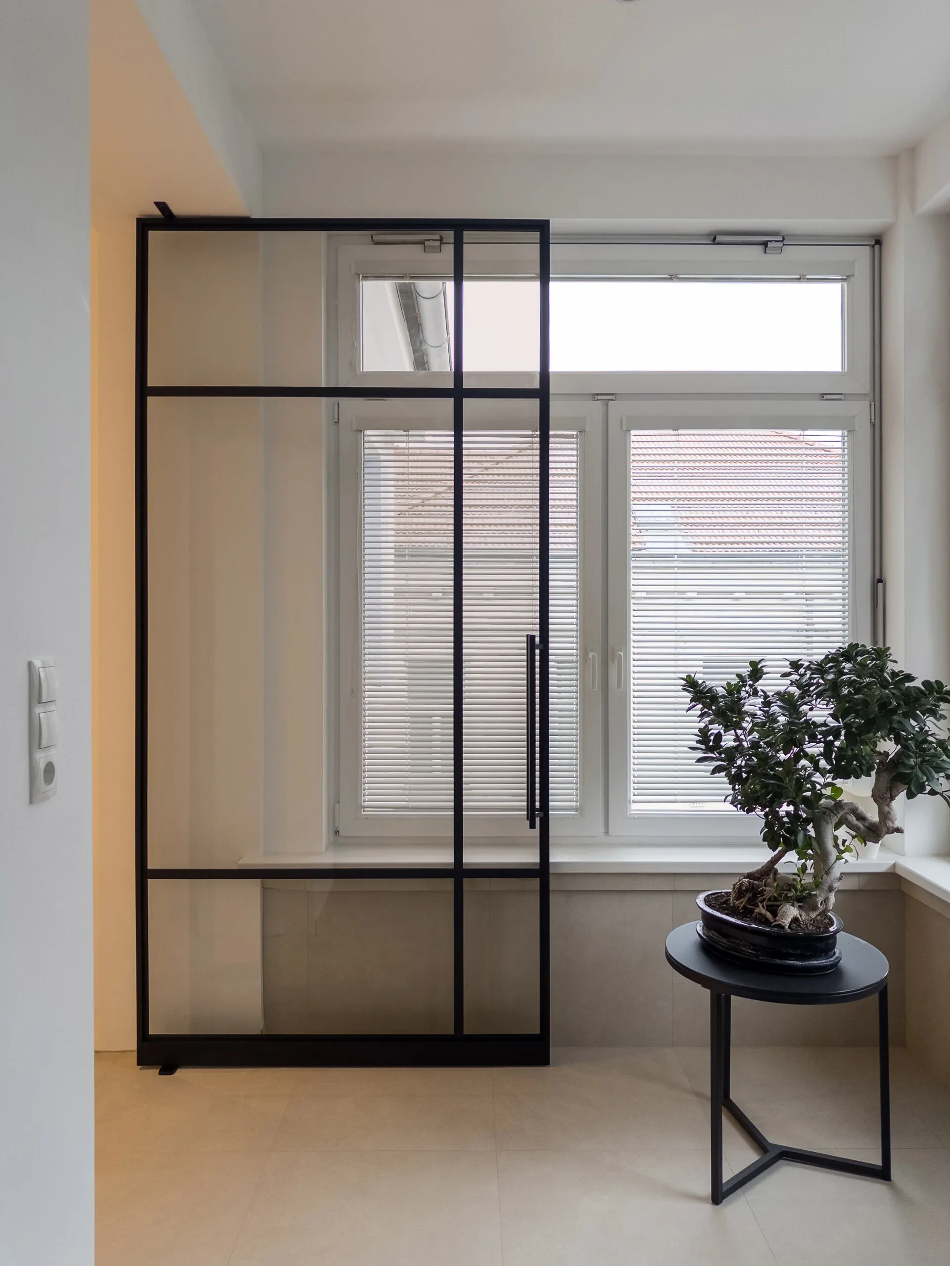 Dieselbe schwarze Pivottür mit Bronzeglas — transparent mit warmer, bronzefarbener Tönung.