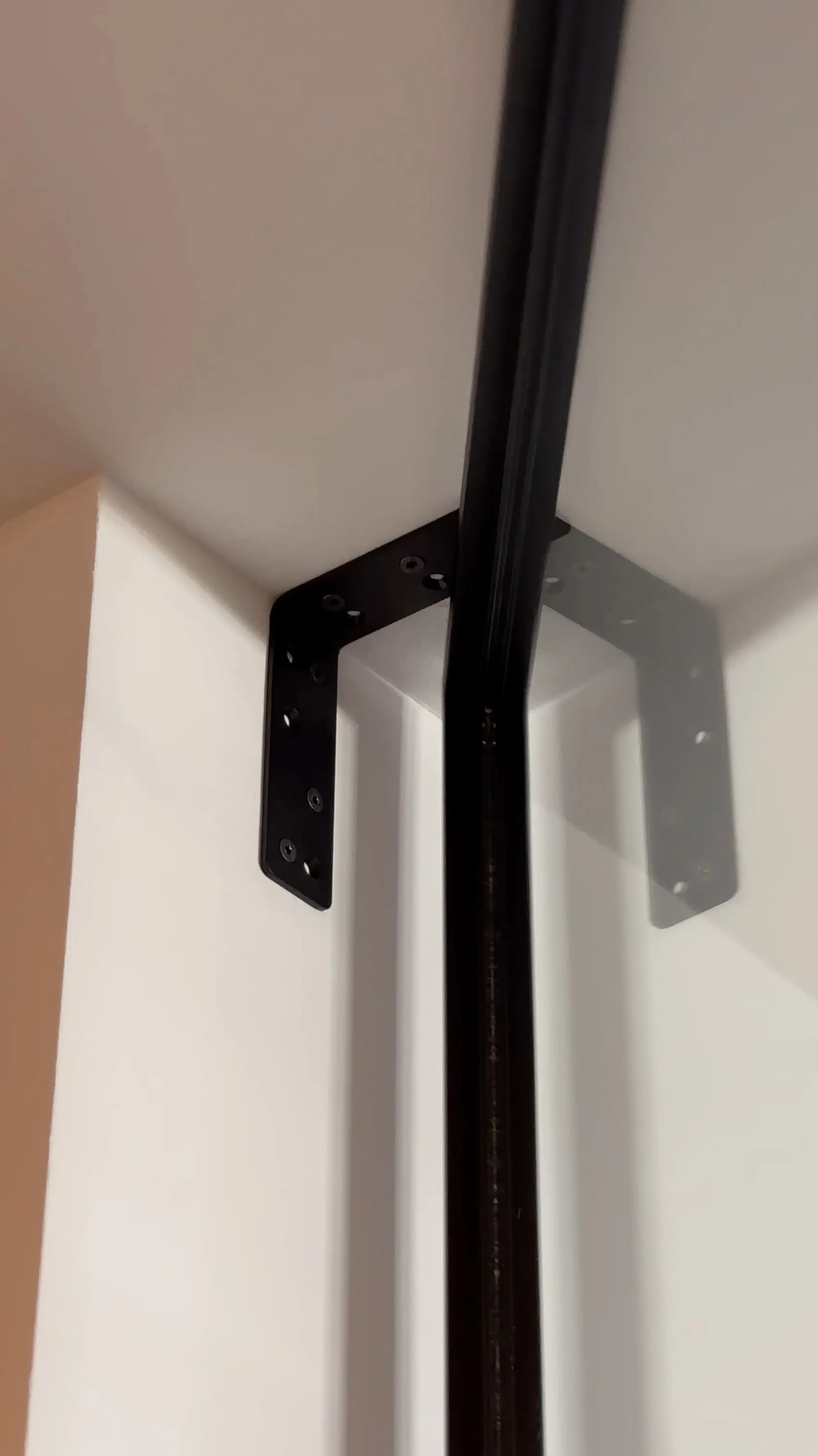 Detail des schwarzen L-Profils zur Deckenbefestigung der Pivottür bei Deckenheizung