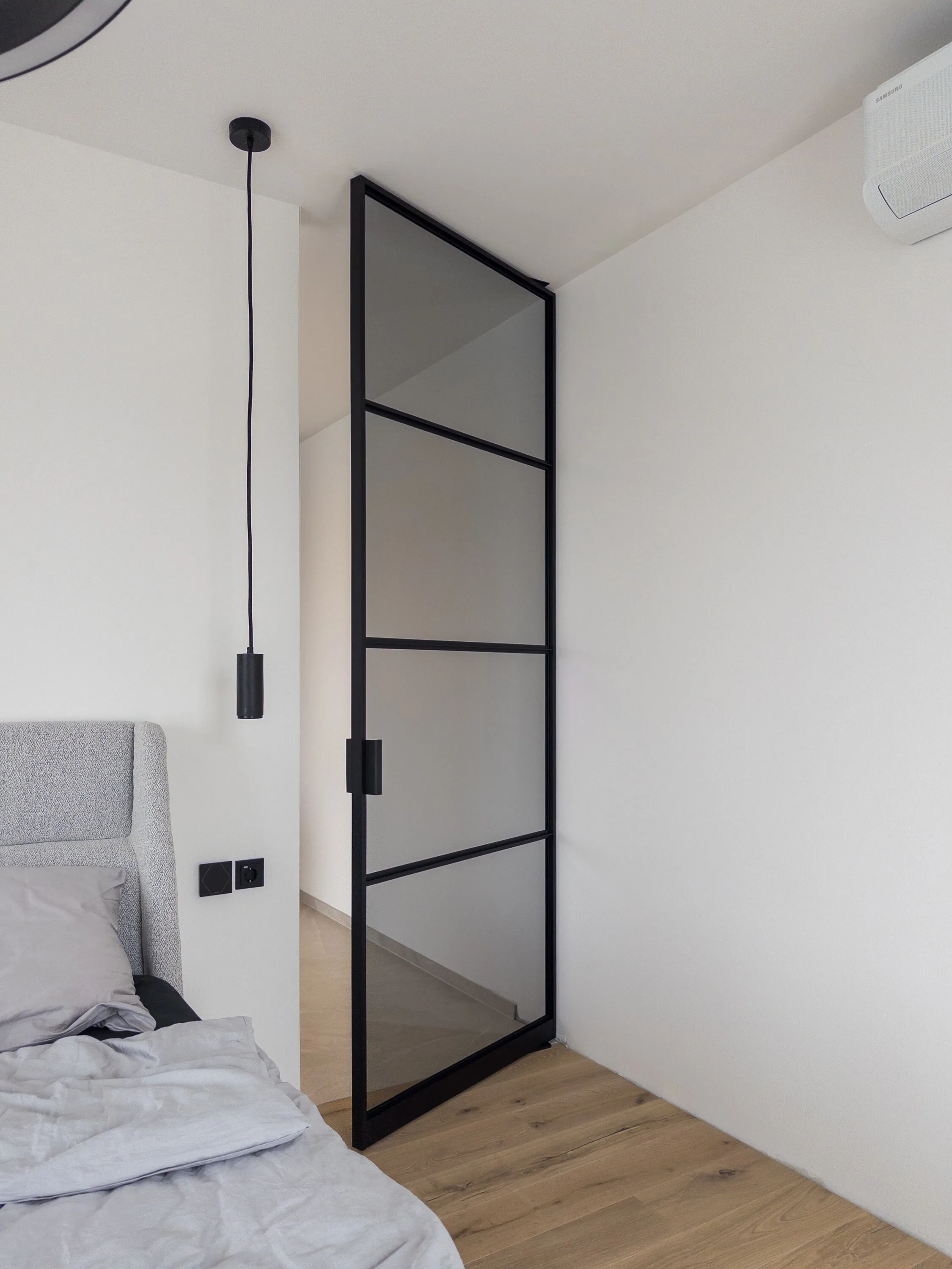 Geöffnete schwarze Grauglas-Pivottür vom Schlafzimmer aus gesehen