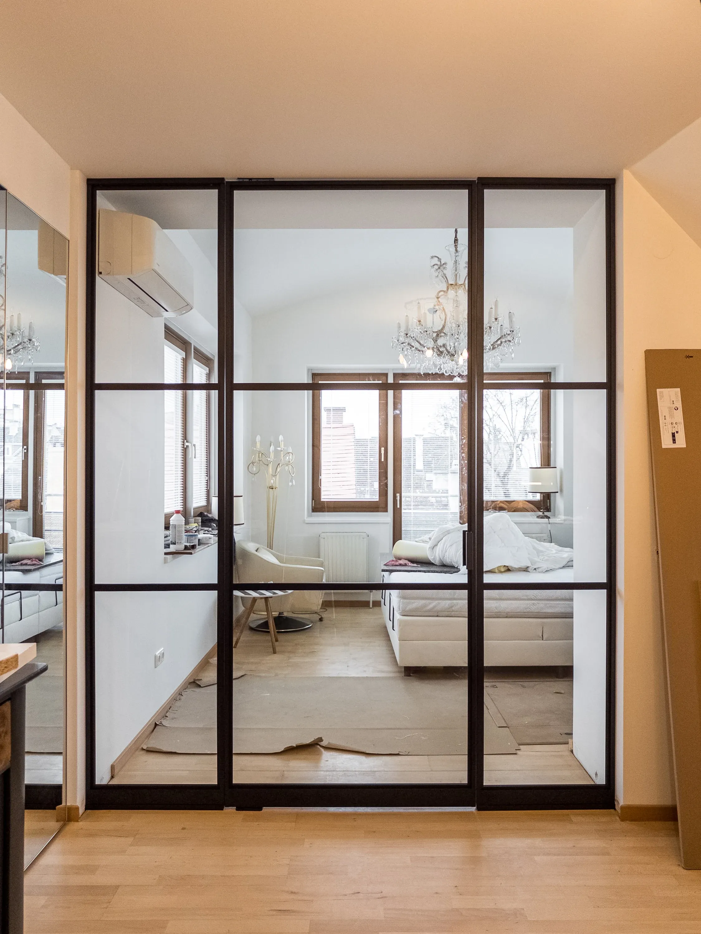 Geschlossene schwarze Pivottür mit zwei festen Seitenelementen und zwei horizontalen flachen Sprossen vor dem neuen Schlafzimmer in Baden bei Wien