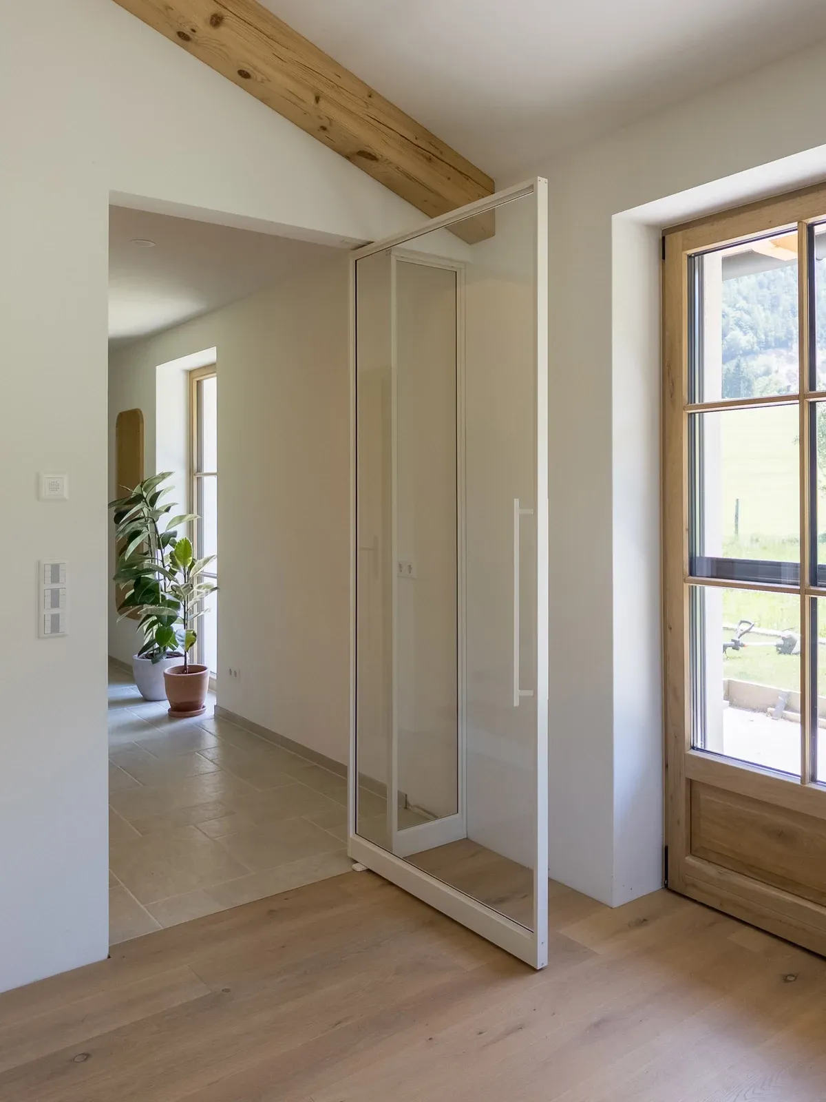 Geöffnete weiße Pivottür mit durchgehender Glasfläche ohne Sprossen.