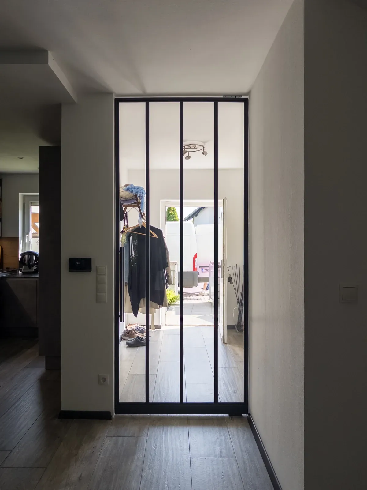 Pivottür mit vertikalen Sprossen und schlanken Glasfeldern.
