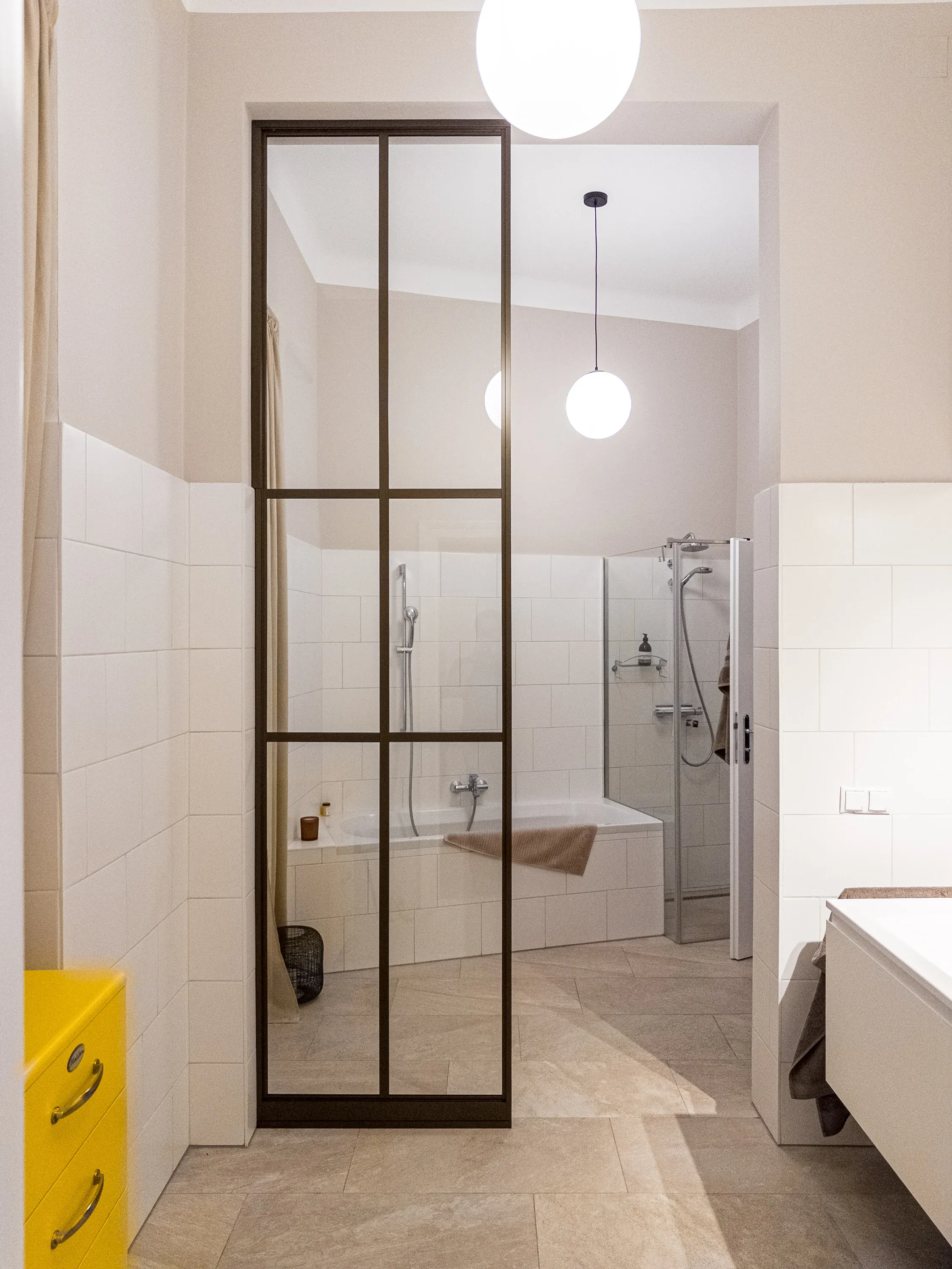 Fester Raumteiler in Bronze mit Klarglas, zwei horizontalen und einer vertikalen Sprosse im renovierten Altbau-Badezimmer in Wien
