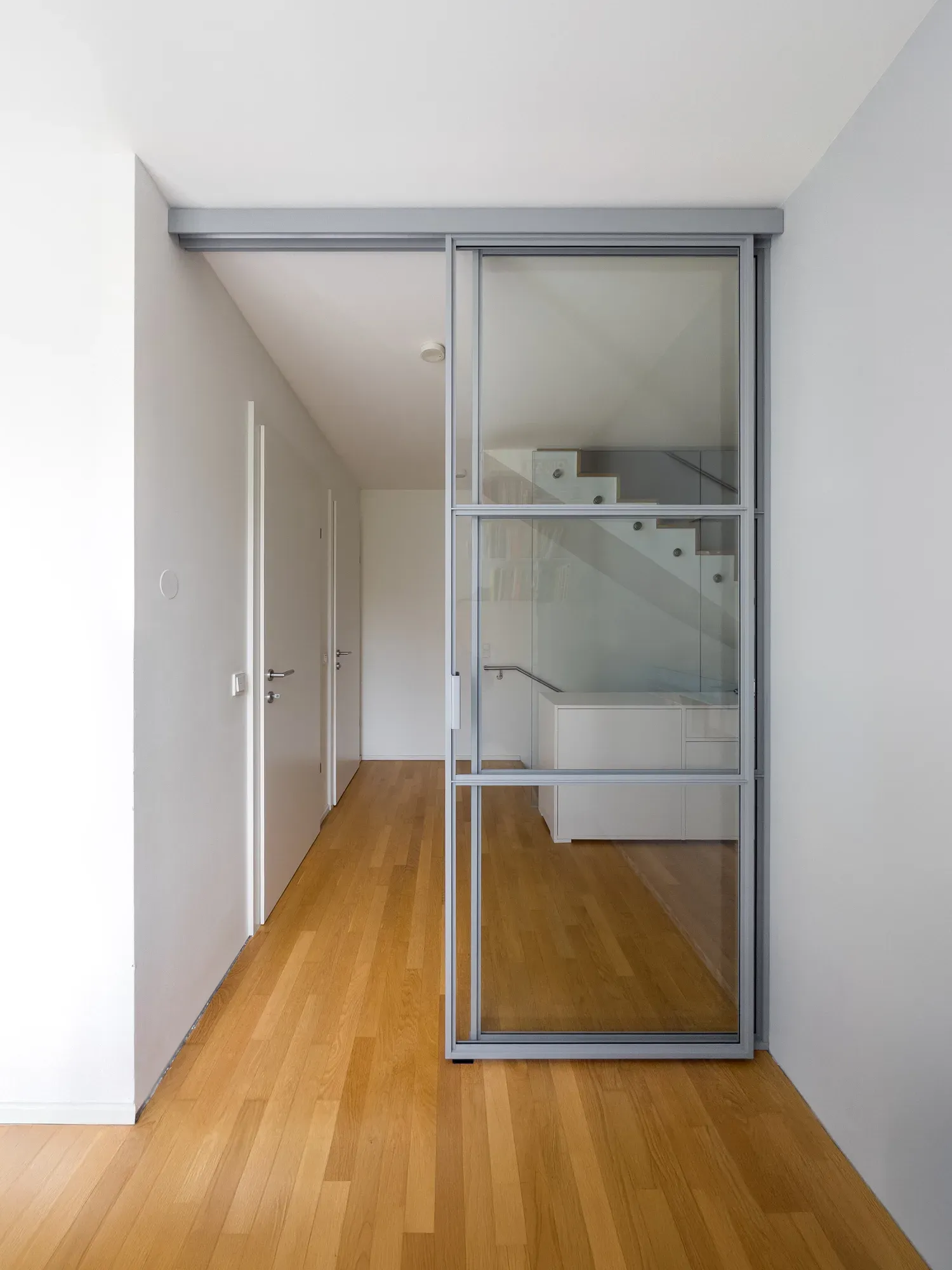 Geöffnete deckenmontierte Schiebetür in RAL 7040 Fenstergrau am Stiegenhaus