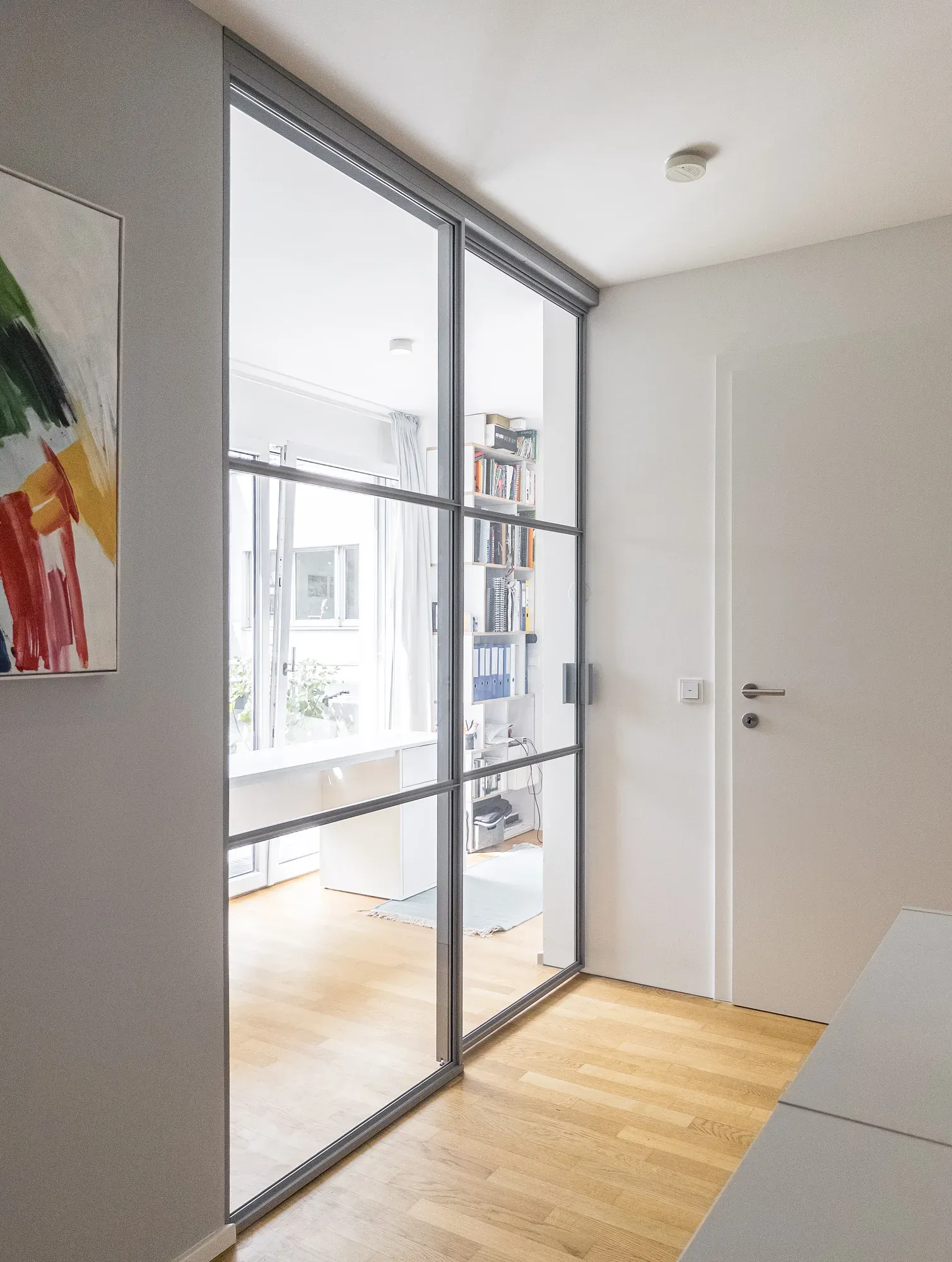 Geschlossene Schiebetür in Fenstergrau als Raumteilung zwischen Stiegenhaus und Home-Office