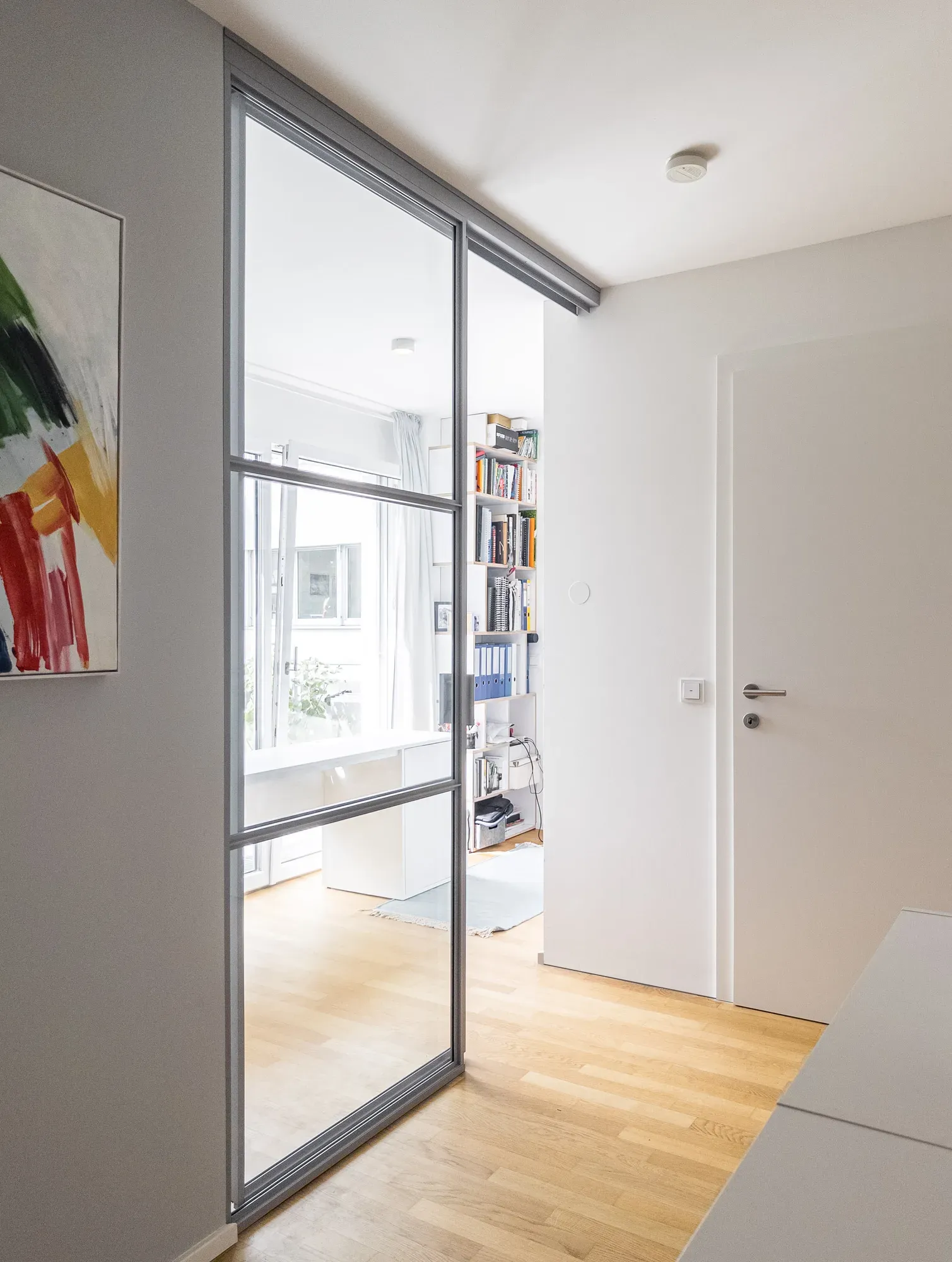 Teilweise geöffnete Schiebetür in RAL 7040 Fenstergrau zwischen Stiegenhaus und Home-Office